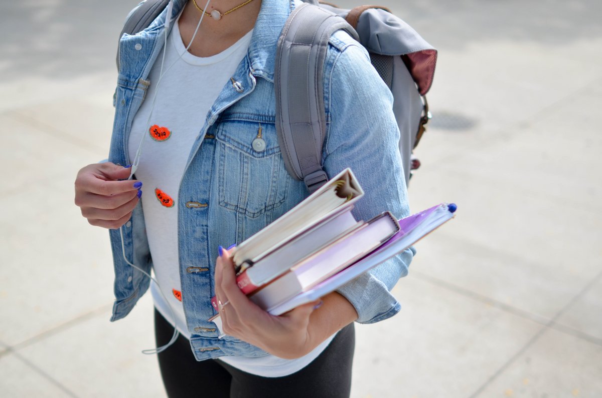 Eine Studierende trägt Lernbücher mit sich.