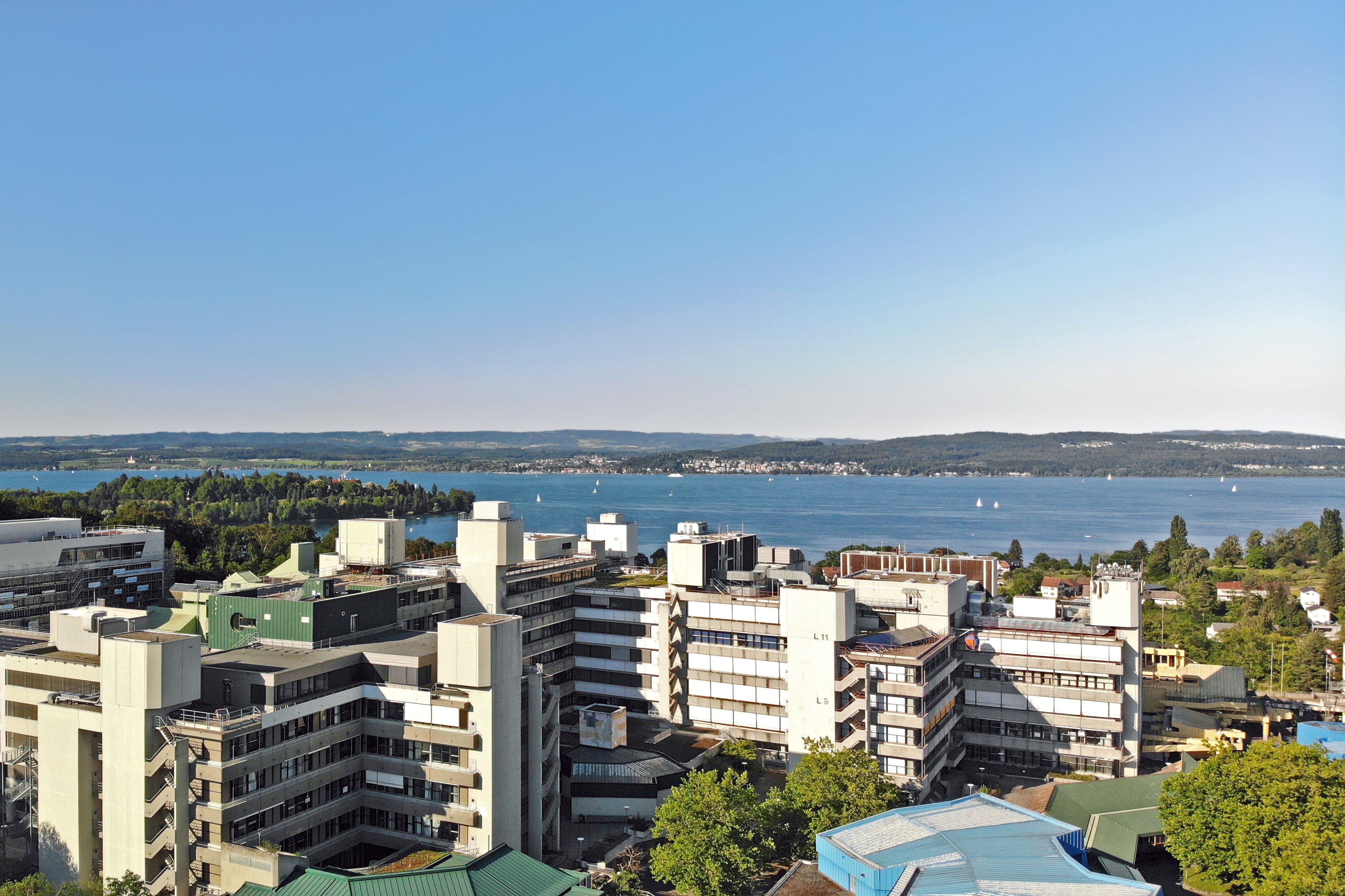 Luftbilder der Universität Konstanz im Sommer mit dem Bodensee und der Insel Mainau im Hintergrund.