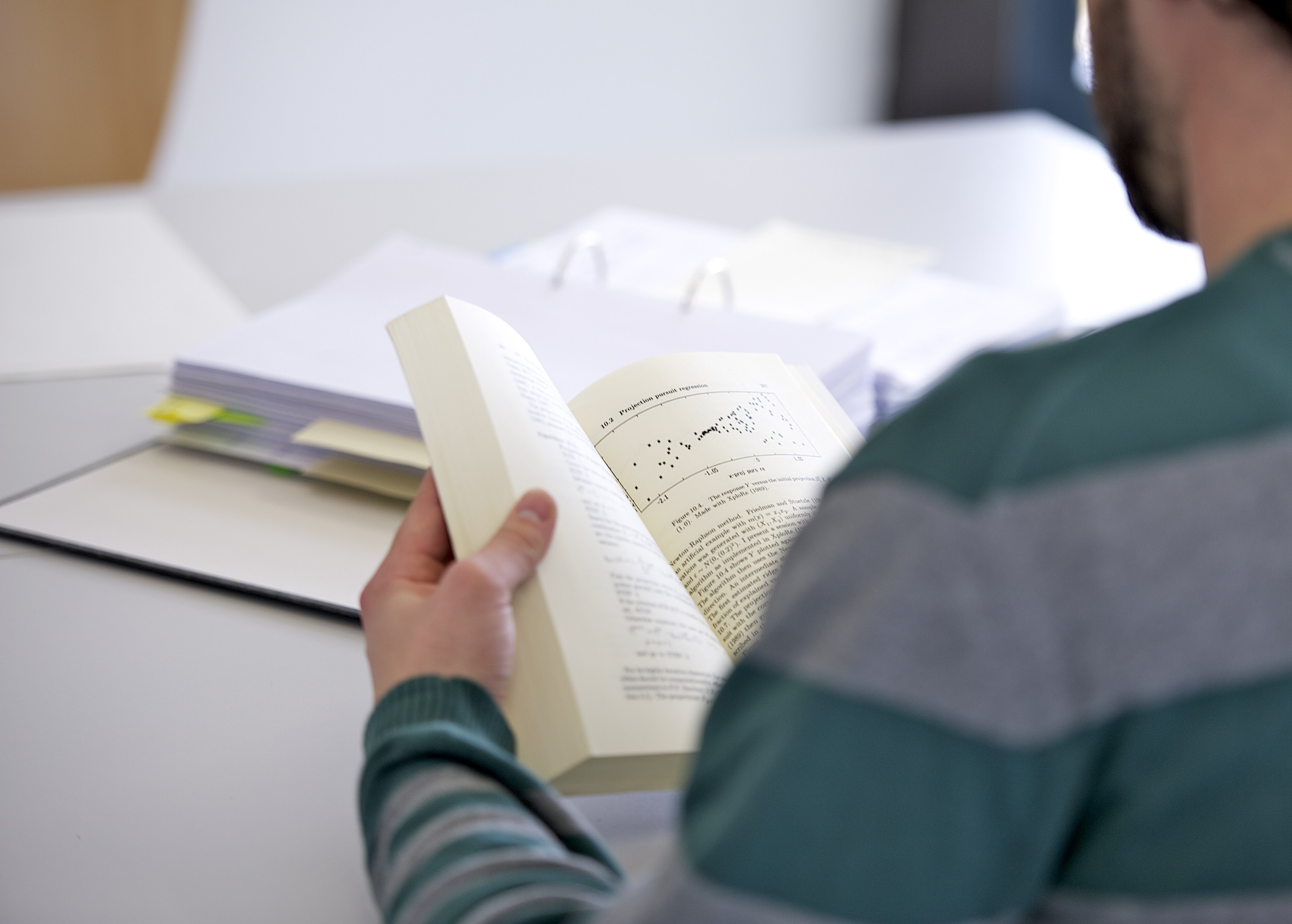 Student mit Buch über quantitative Forschungsmethoden