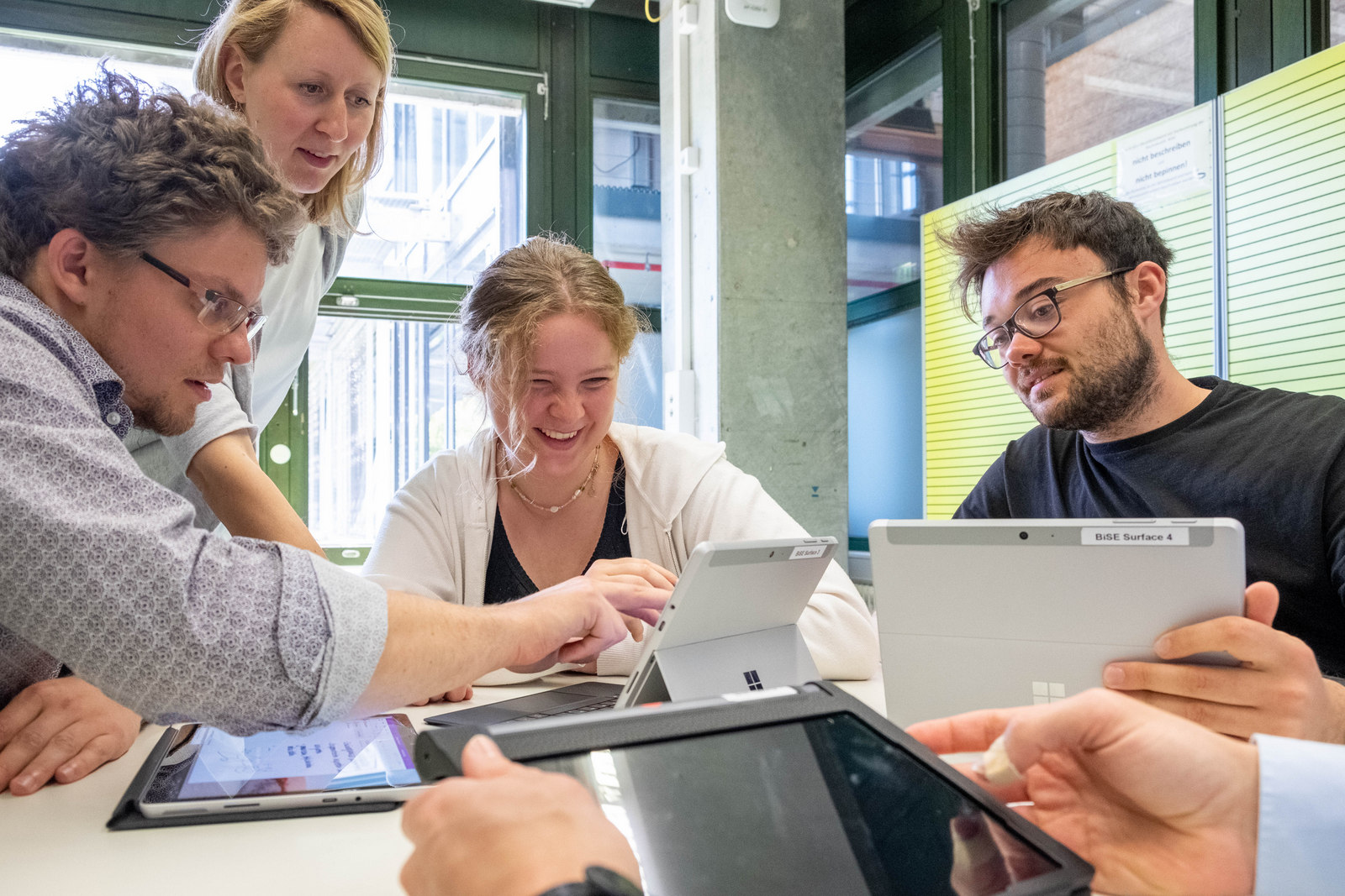 Lehrperson unterstützt Studierende am Tablet 